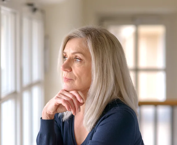 Older woman looking out the window with hand under her chin