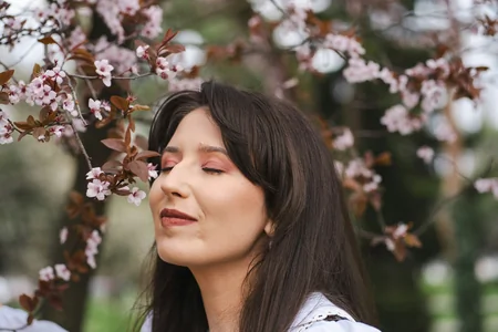 Woman smelling cherry blossoms to bring feelings of calm